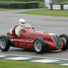 Goodwood Revival roter Oldtimer mit Fahrer auf Rennstrecke