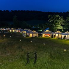 Eine Vielzahl festlich beleuchteter Marquees im Garten bei Dunkelheit